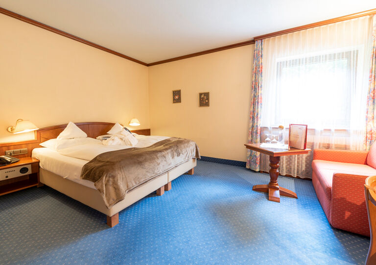 Ein Doppelbett in einem Hotelzimmer im Rindererhof