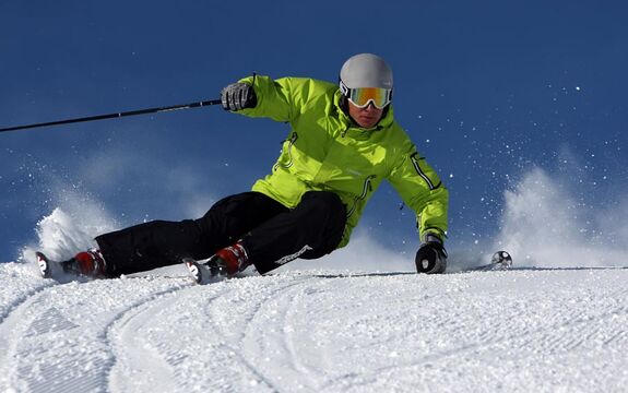 Ein Skifahrer fährt gerade einen steilen Schwung auf einer Piste