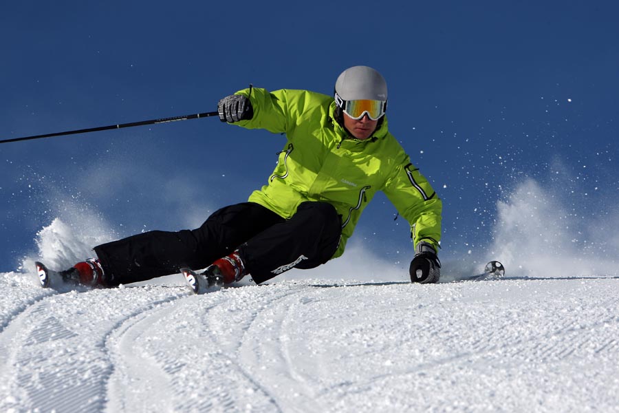 A skier is making a steep turn on a ski slope